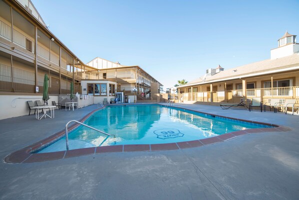 A swimming pool with a 'Route 66' design, surrounded by outdoor seating and a building with balconies.