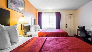 Une chambre d’hôtel avec deux lits, un bureau, une chaise, une lampe et une porte.