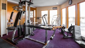 Une salle de sport équipée de divers appareils d’exercice, notamment un banc de développé couché, un tapis de course et une machine de musculation.