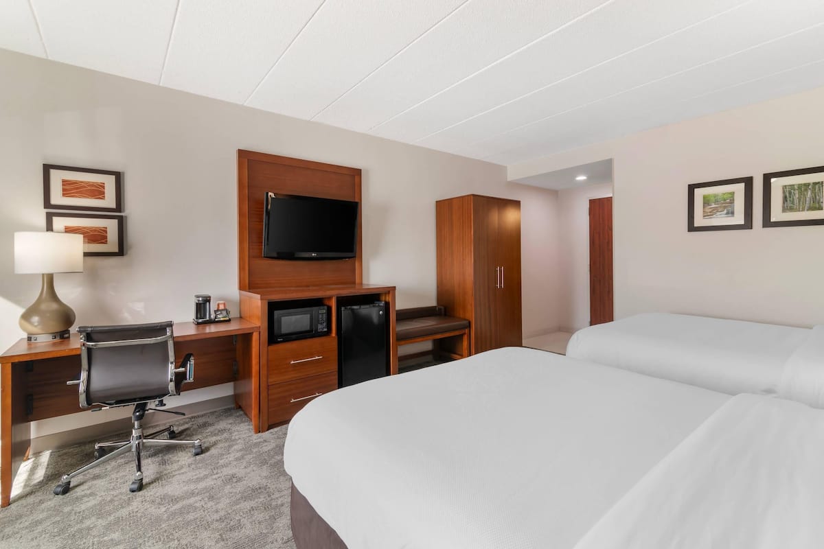 A hotel room with a bed, a desk with a computer, a television, and a wardrobe.