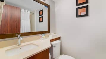 A bathroom with a sink, mirror, toilet, and framed pictures on the wall.