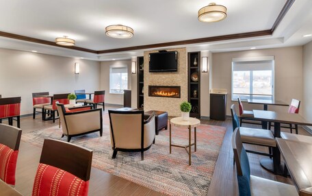 A hotel lobby with a fireplace, seating areas, and a television mounted on the wall.