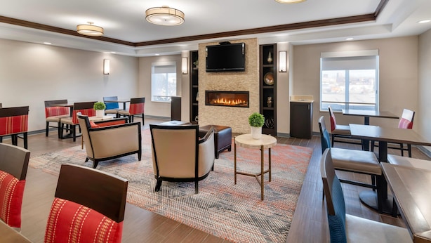 A hotel lobby with a fireplace, seating areas, and a television mounted on the wall.