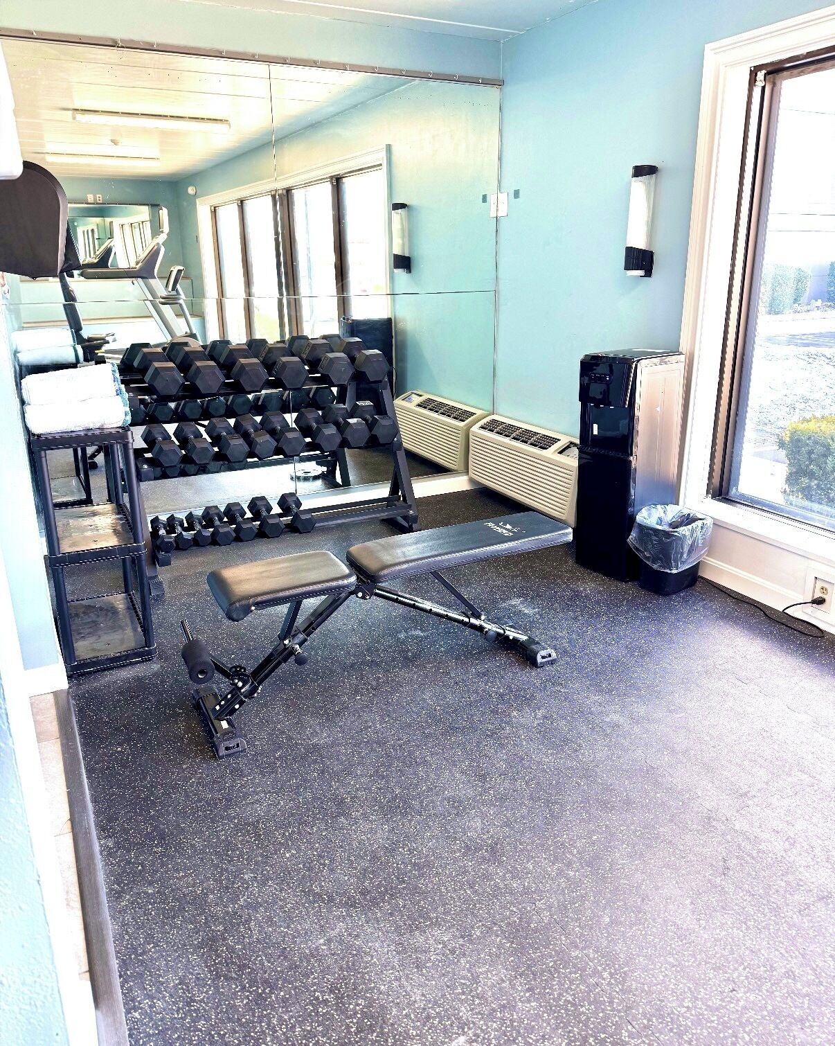 A gym with exercise equipment, a bench, and a water dispenser.