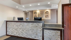 A reception area with a modern design, including a reception desk, a wall-mounted welcome sign, and a decorative wall panel.