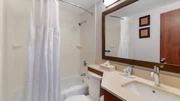 A bathroom with a shower curtain, a bathtub, a toilet, a sink, and a mirror.