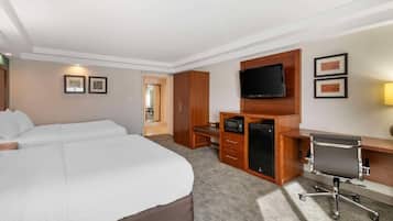 Quarto de hotel com uma cama grande, uma escrivaninha com computador, televisão e micro-ondas.