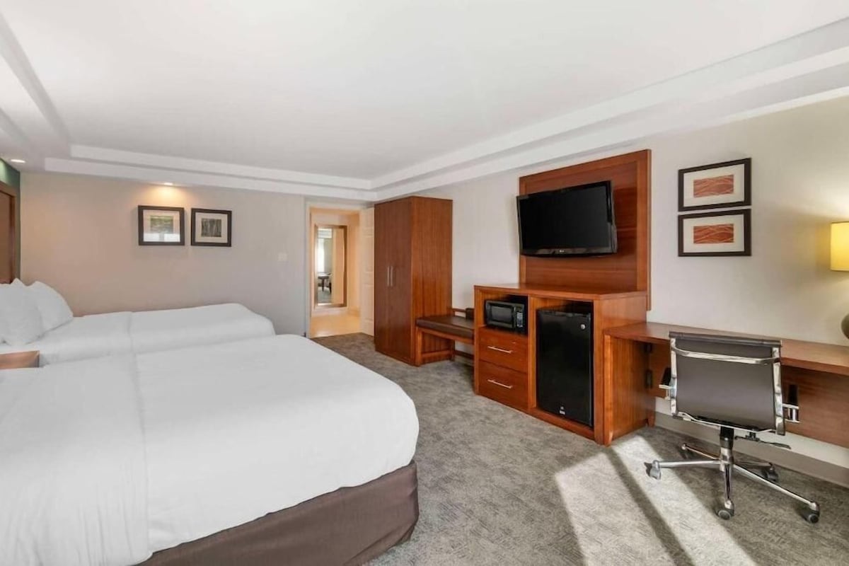A hotel room with a large bed, a desk with a computer, a television, and a microwave.