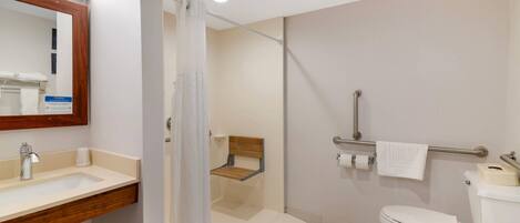 A bathroom with a sink, toilet, shower, and a wooden bench.