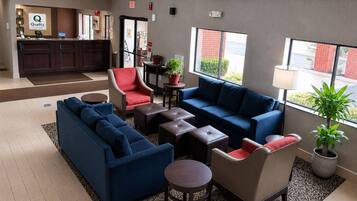 A hotel lobby with a reception desk, seating area, and large windows.