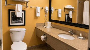 A hotel bathroom with a toilet, sink, and a large mirror.