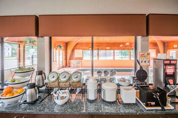 A breakfast buffet setup with various food items and drink dispensers. - Quality Inn Corning (Corning)