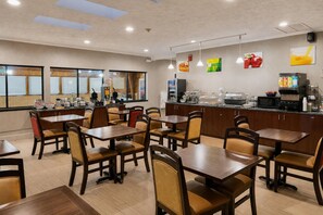 A restaurant with multiple tables and chairs, a counter with food and drink dispensers, and a view through large windows. - Quality Inn Corning (Corning)
