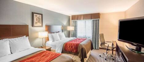 A hotel room with two beds, a desk, a television, and a window with curtains.