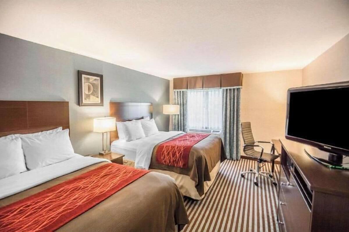 Una habitación de hotel con dos camas, televisión y un escritorio con silla.