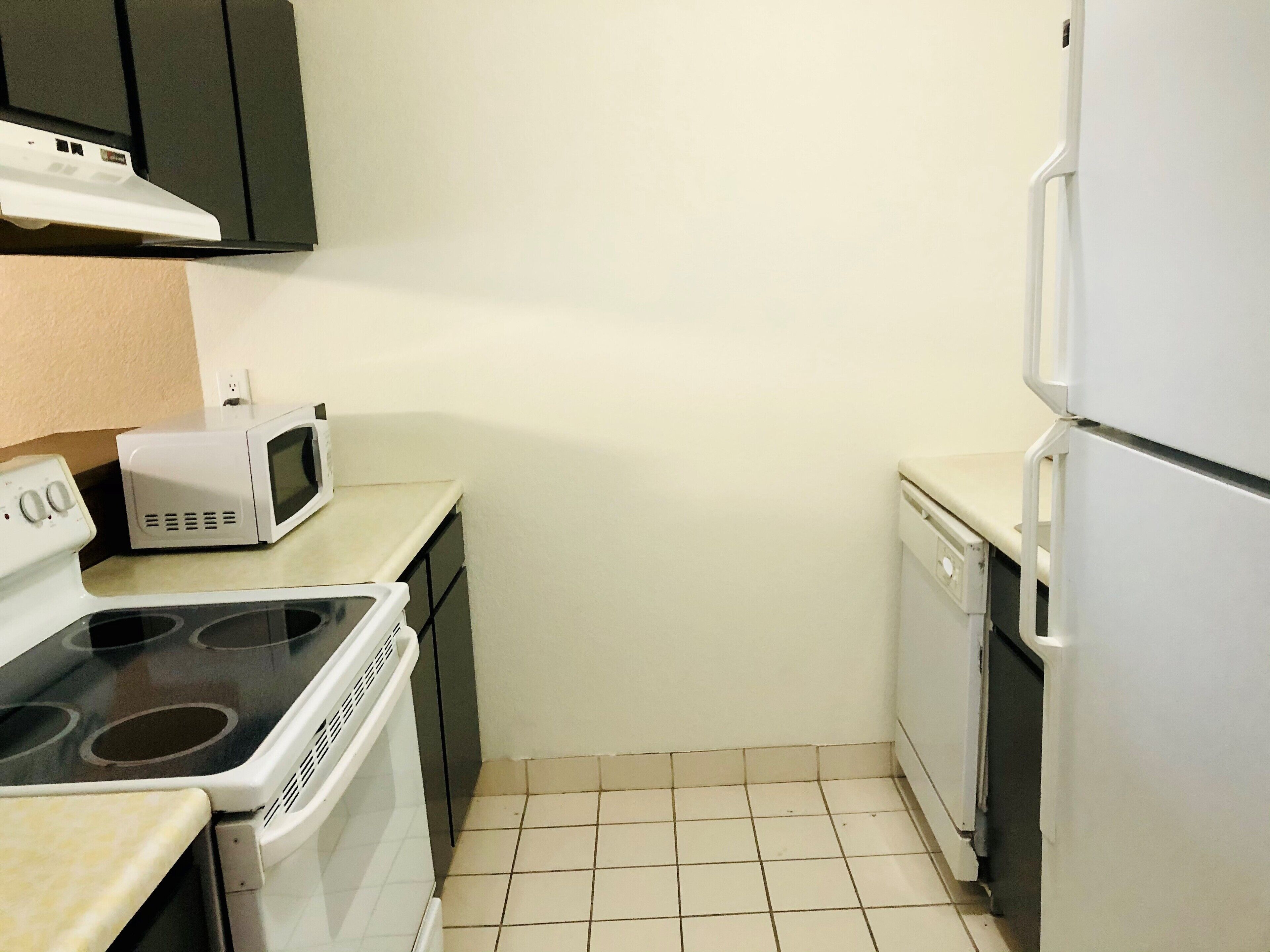 Una cocina compacta con estufa, microondas, lavavajillas y refrigerador.