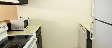 Una cocina compacta con estufa, microondas, lavavajillas y refrigerador.
