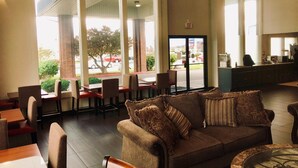 A spacious lobby with a large window, a sofa with patterned cushions, and a counter area.