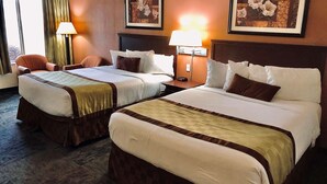 A hotel room with two beds, a chair, and two lamps.