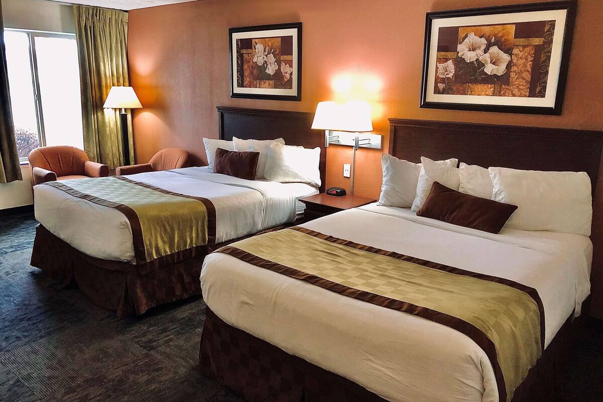 Ein Hotelzimmer mit zwei Betten, einem Sessel und zwei Lampen.