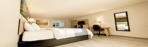 Een hotelkamer met een bed, bureau, stoel, televisie en kunstwerken aan de muur.