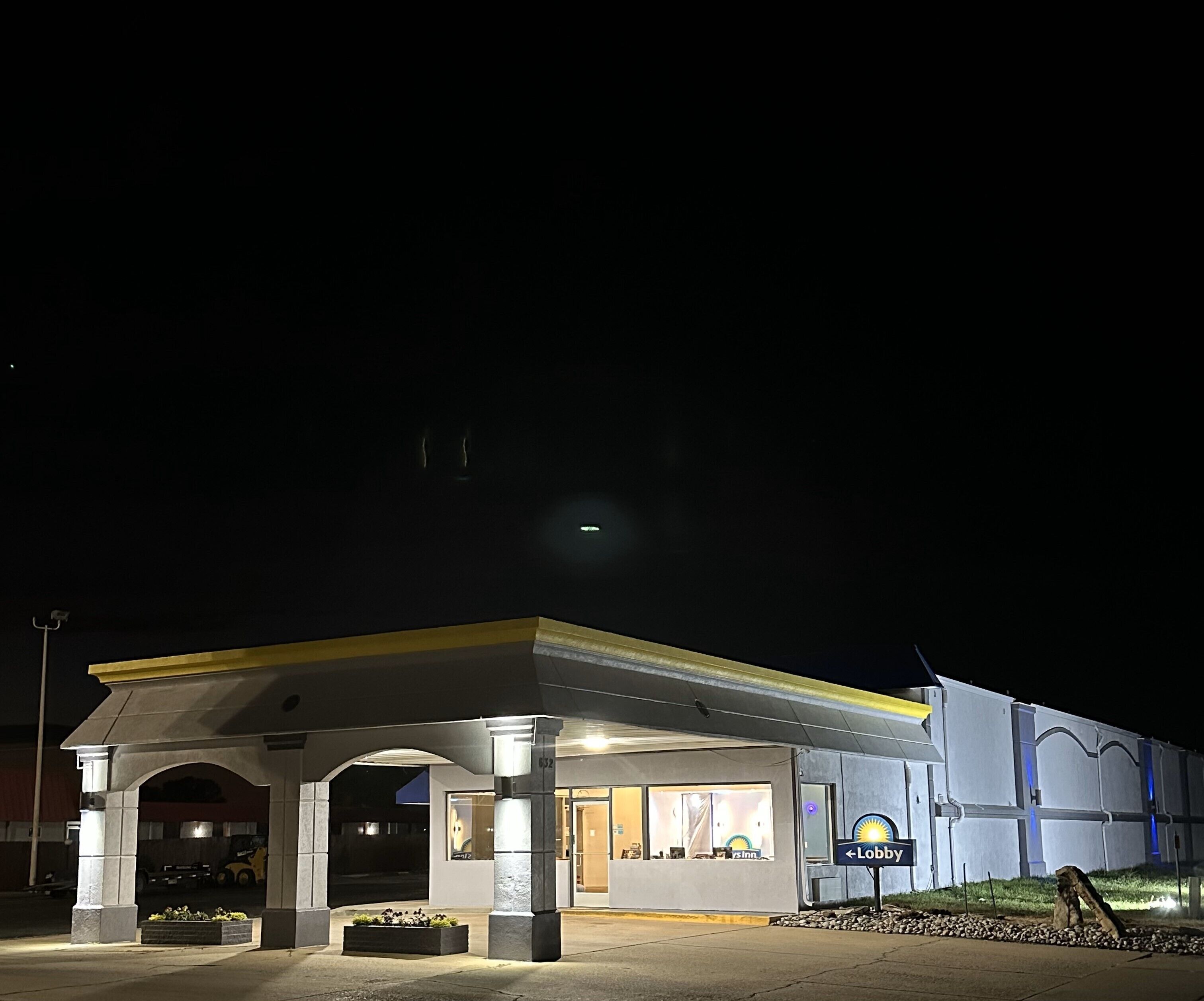 A well-lit hotel with a covered lobby area, a visible reception desk, and a sign indicating the lobby direction.