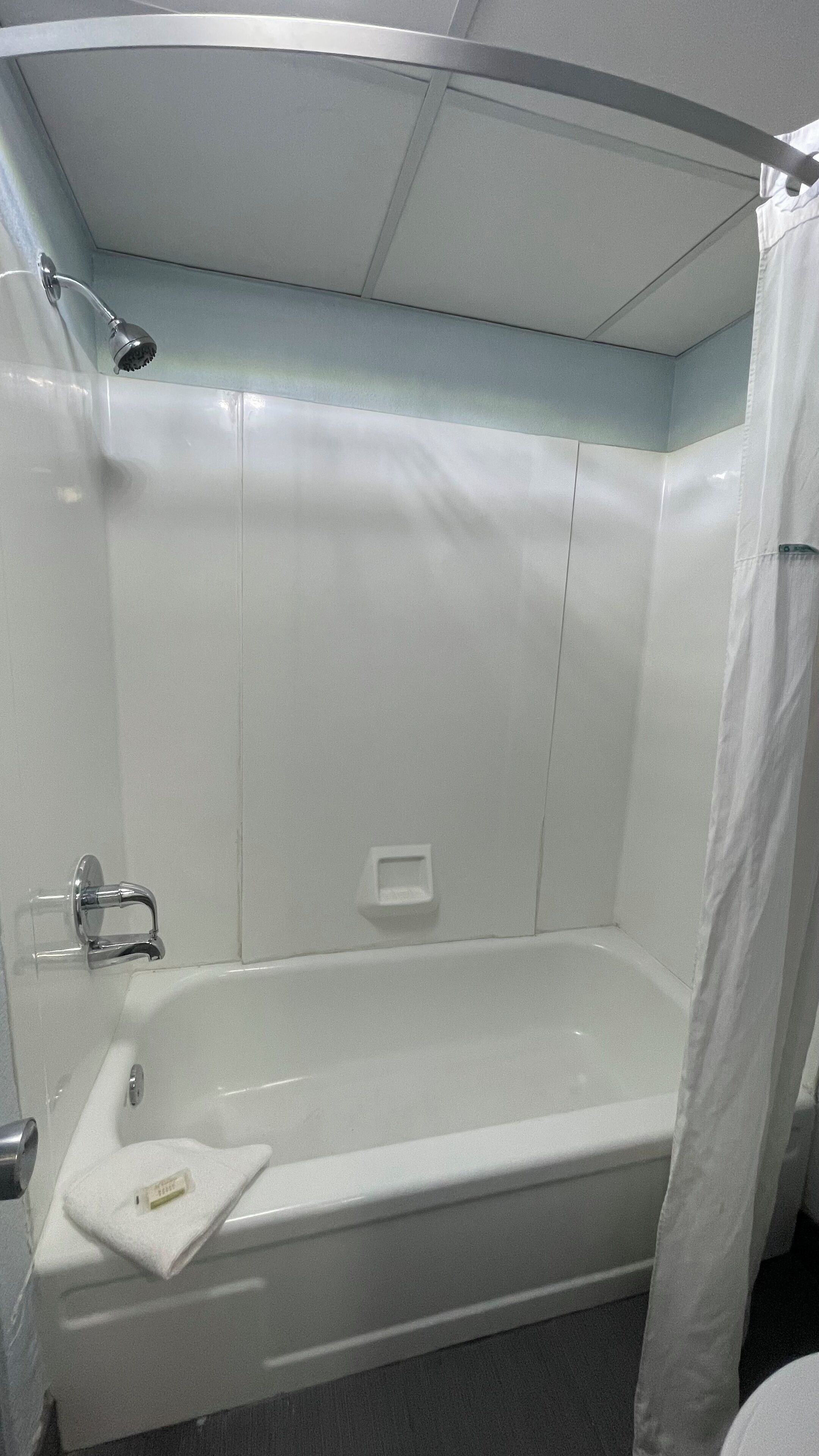 Une salle de bain avec une baignoire, une douche et une serviette sur le sol.