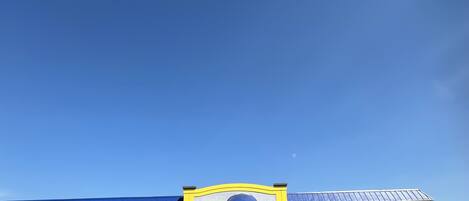 A multi-story motel with a blue and yellow facade, a covered entrance, and a parking lot.