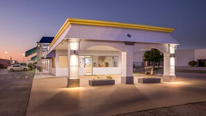 A modern building with a covered entrance, large windows, and outdoor seating areas.