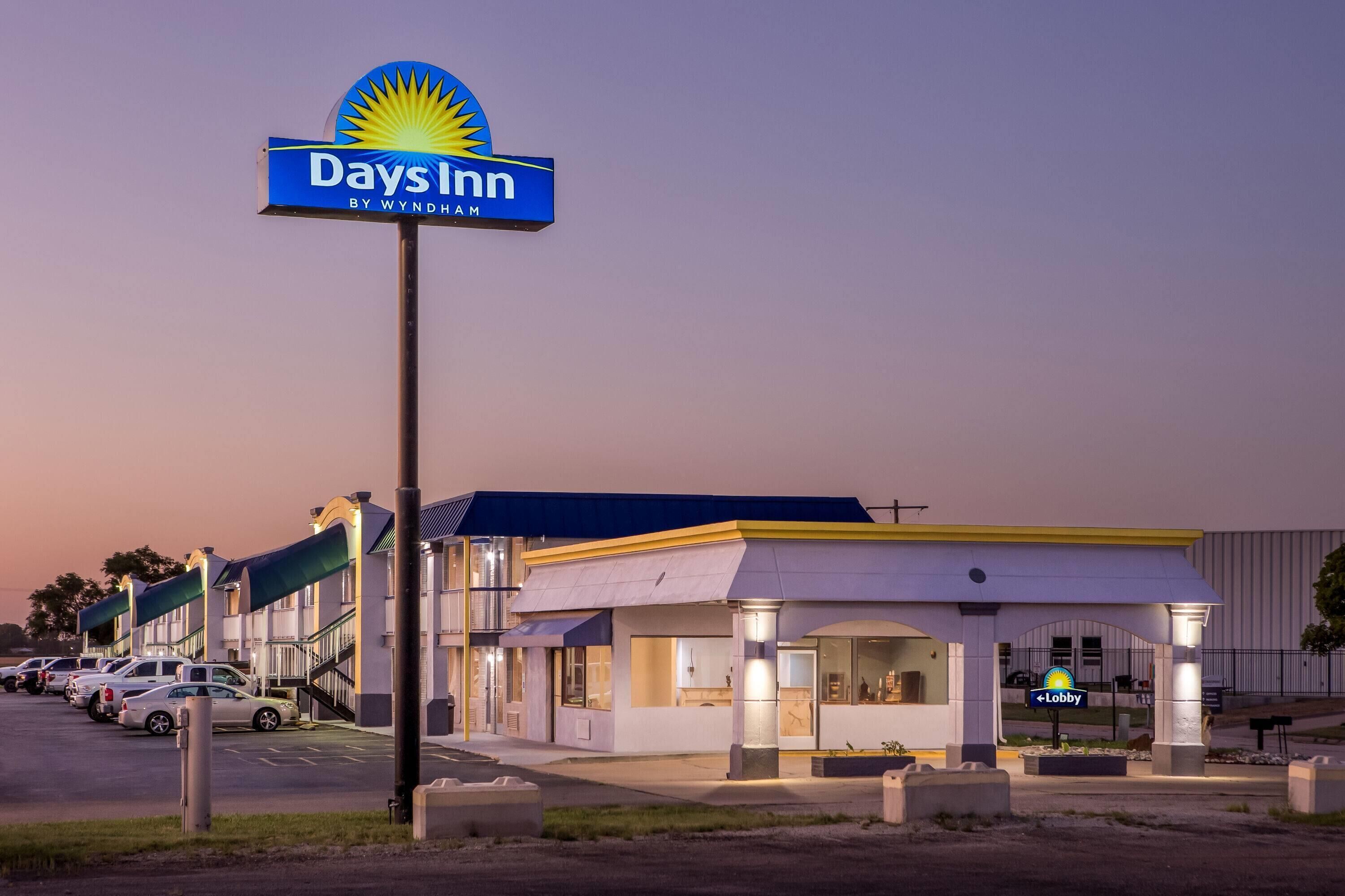 A Days Inn hotel with a prominent sign, a parking lot, and a building with a flat roof.