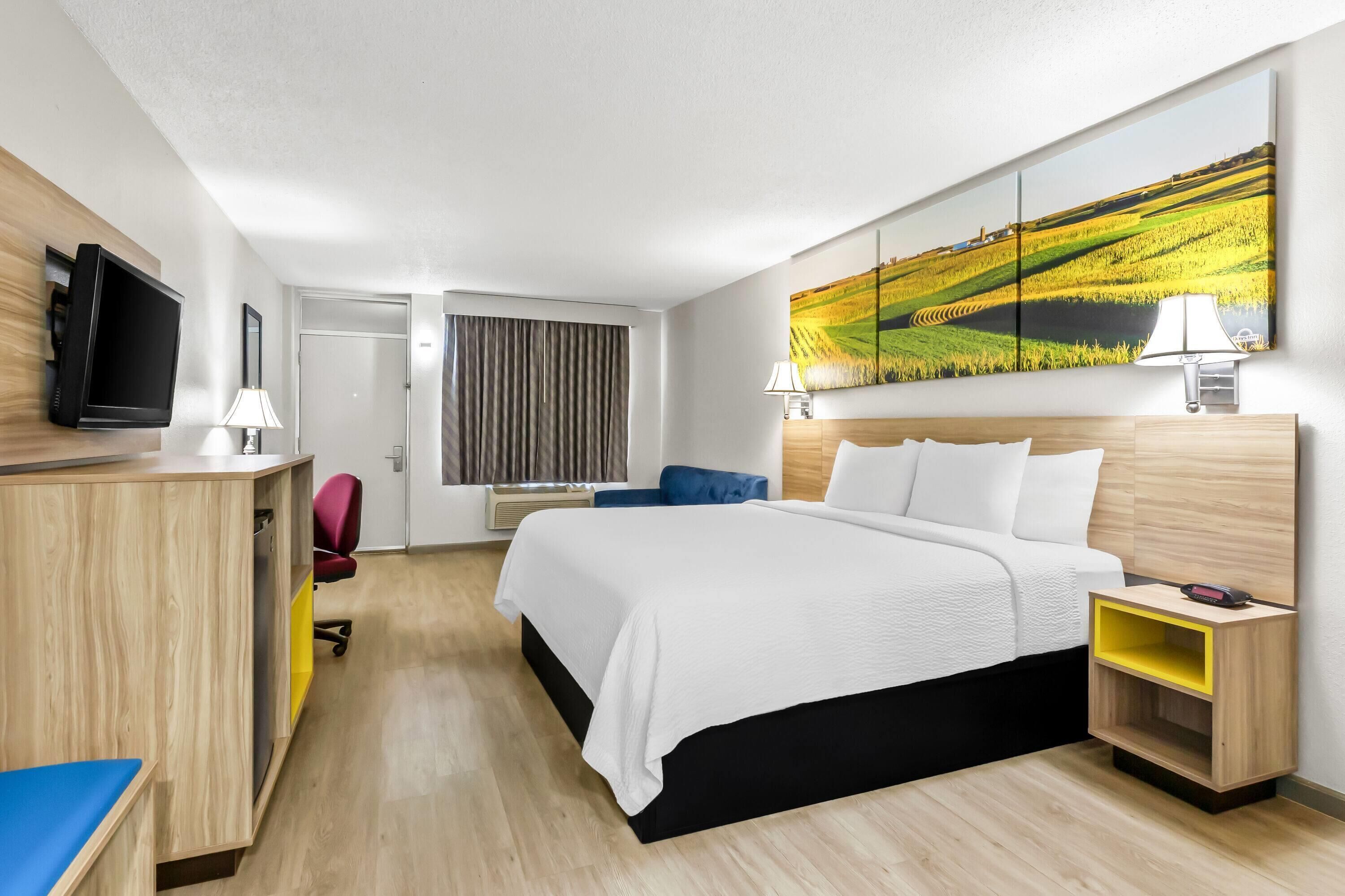 Une chambre d’hôtel moderne équipée d’un lit, d’un bureau et d’une télévision.