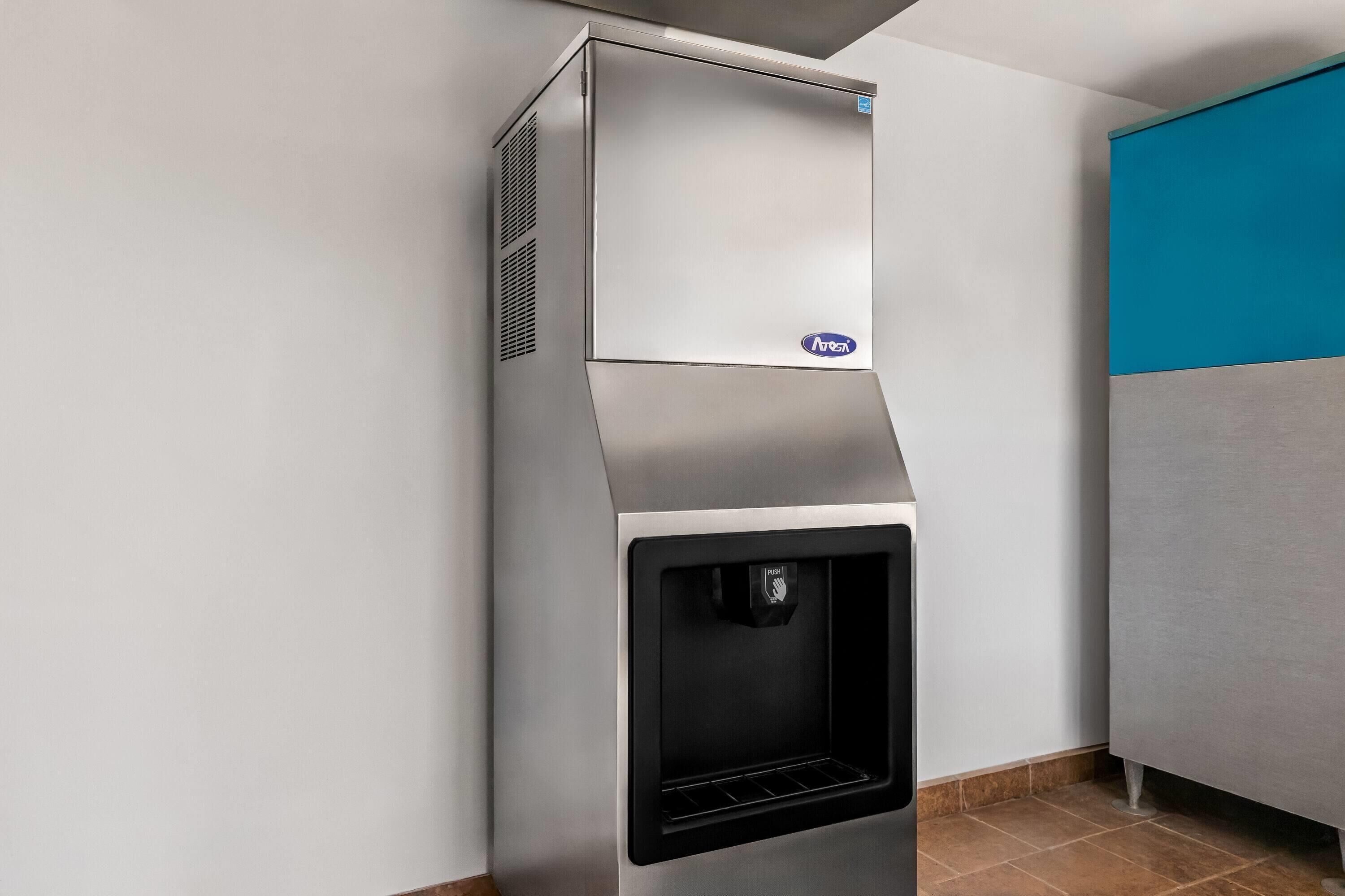 A stainless steel range hood with a built-in water dispenser and a push button.