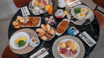 A breakfast setting with various dishes, a teapot, and cutlery on a marble table.