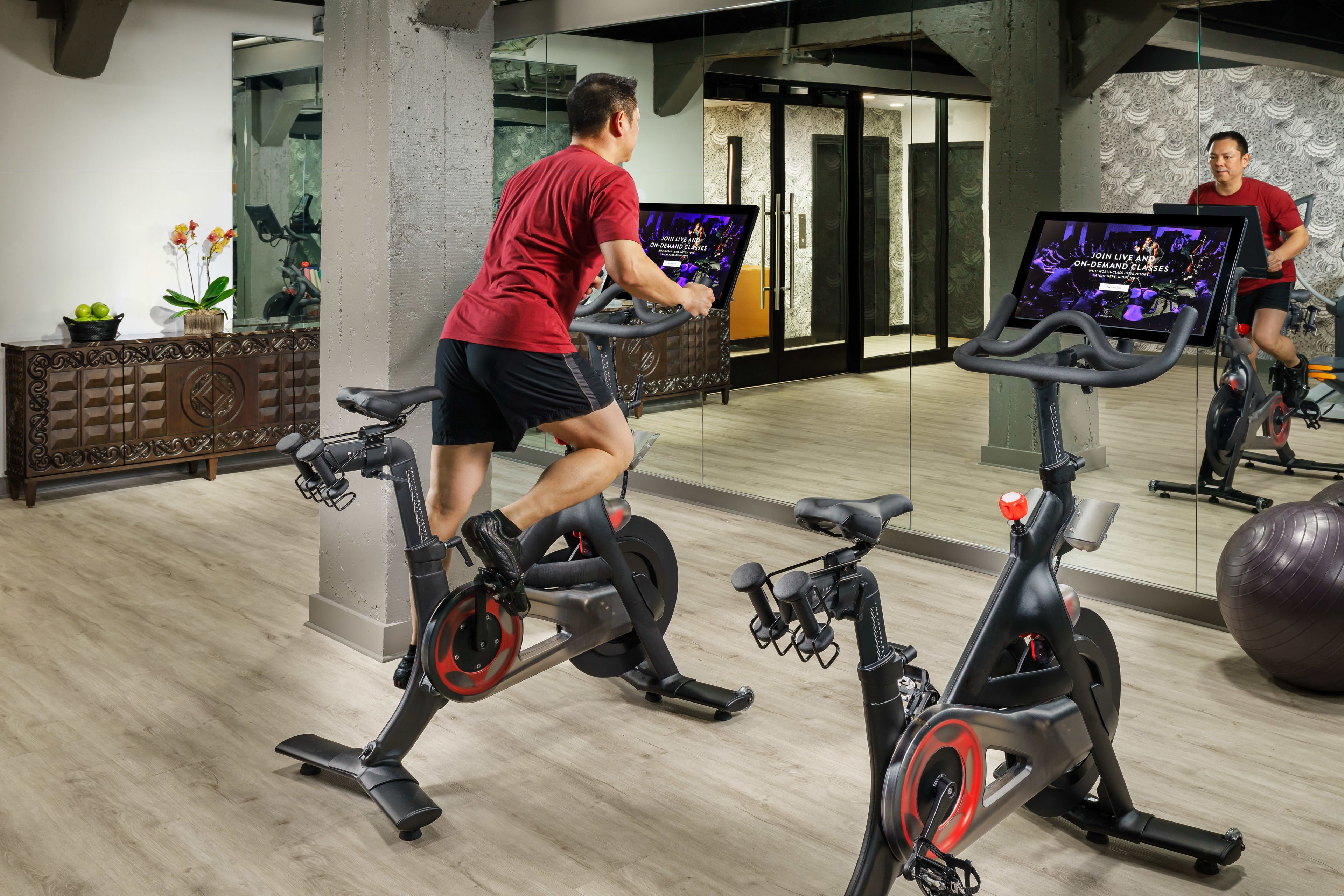 A gym with stationary bikes, a large mirror, and exercise balls.