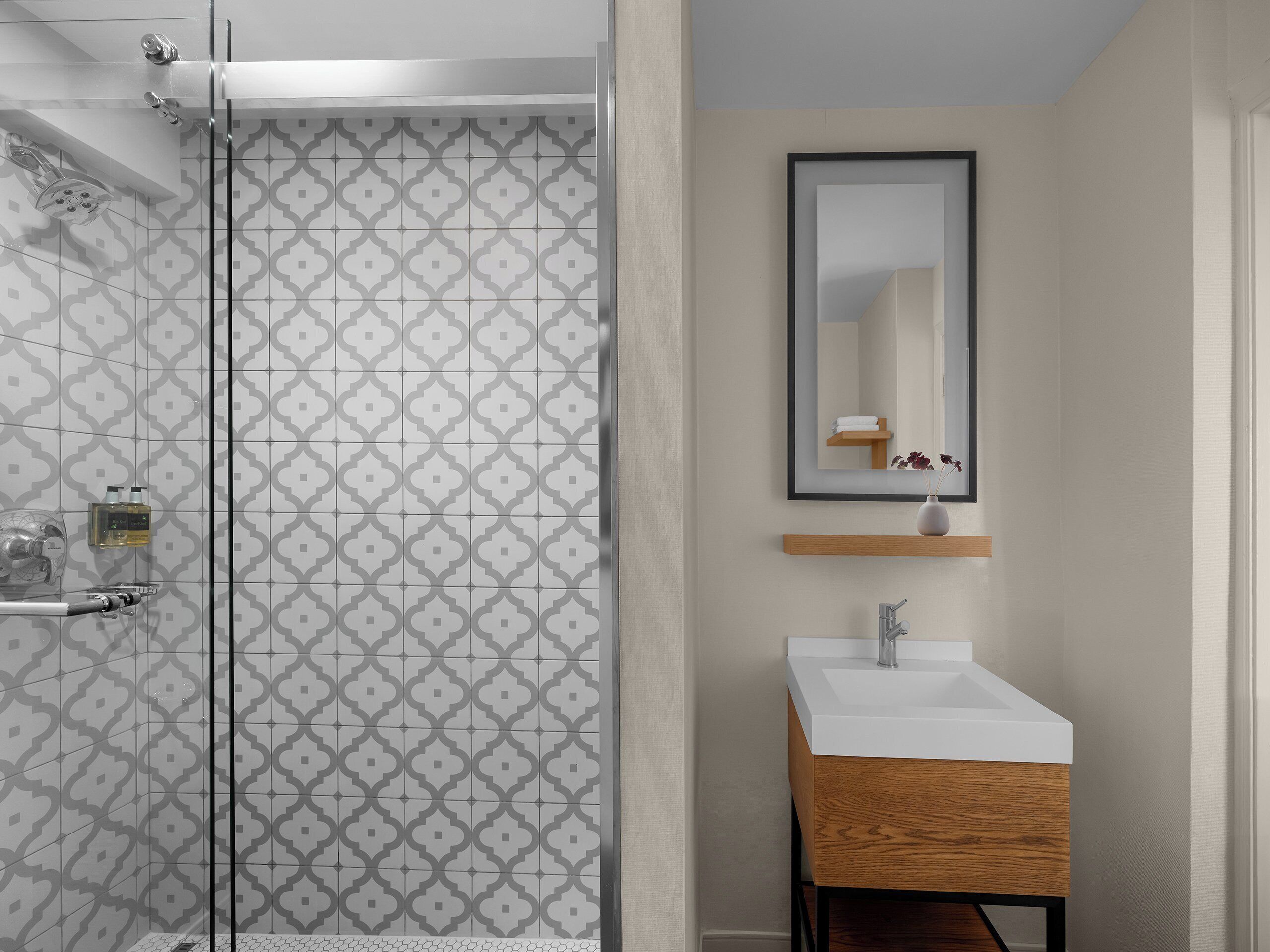 A bathroom with a shower, a sink, and a mirror.