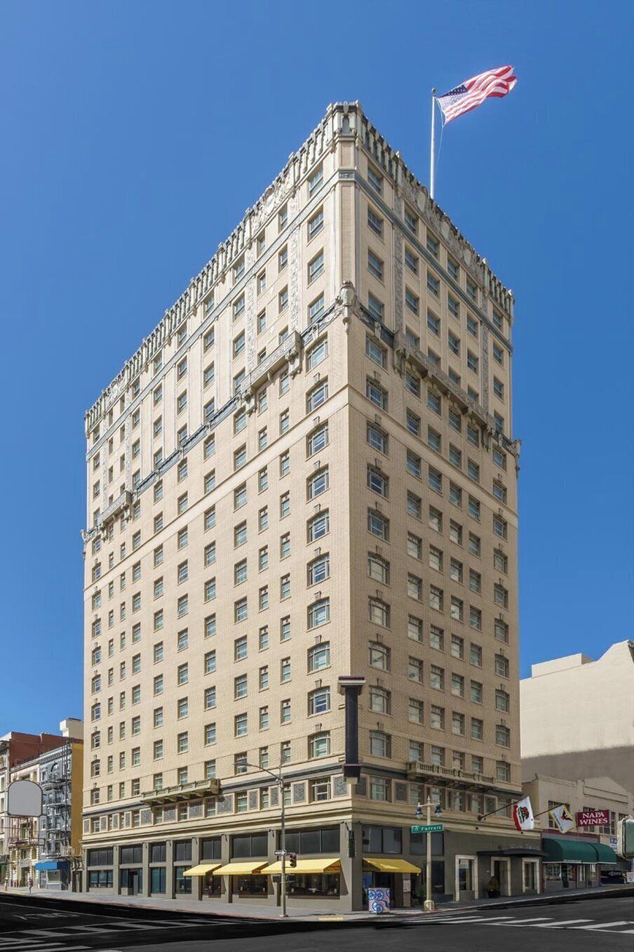 A multi-story hotel with a classic architectural design, featuring a prominent American flag on top.