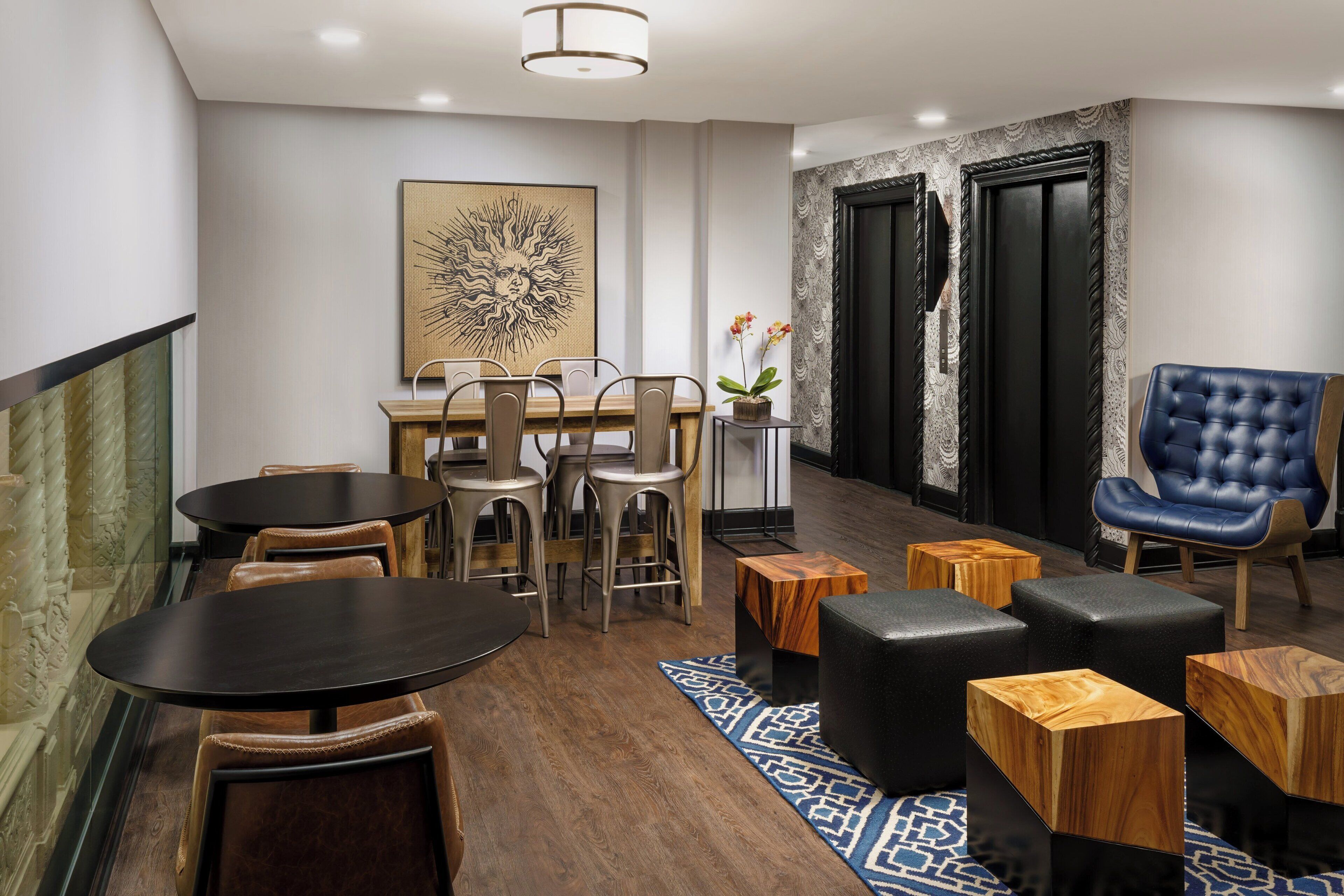 A modern hotel lobby with a dining area, seating, and a decorative wall piece.