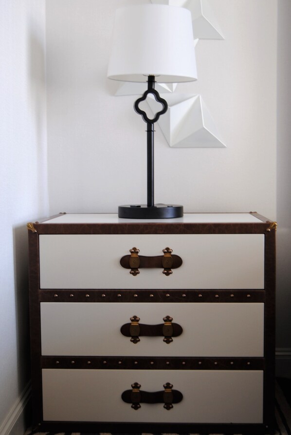 A dresser with a lamp on top, featuring a white and brown color scheme with metallic handles. - Hotel Spero, Vignette Collection by IHG (San Francisco)