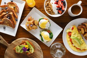 A breakfast spread with toast, eggs, potatoes, and fruit on a wooden table. - Hotel Spero, Vignette Collection by IHG (San Francisco)
