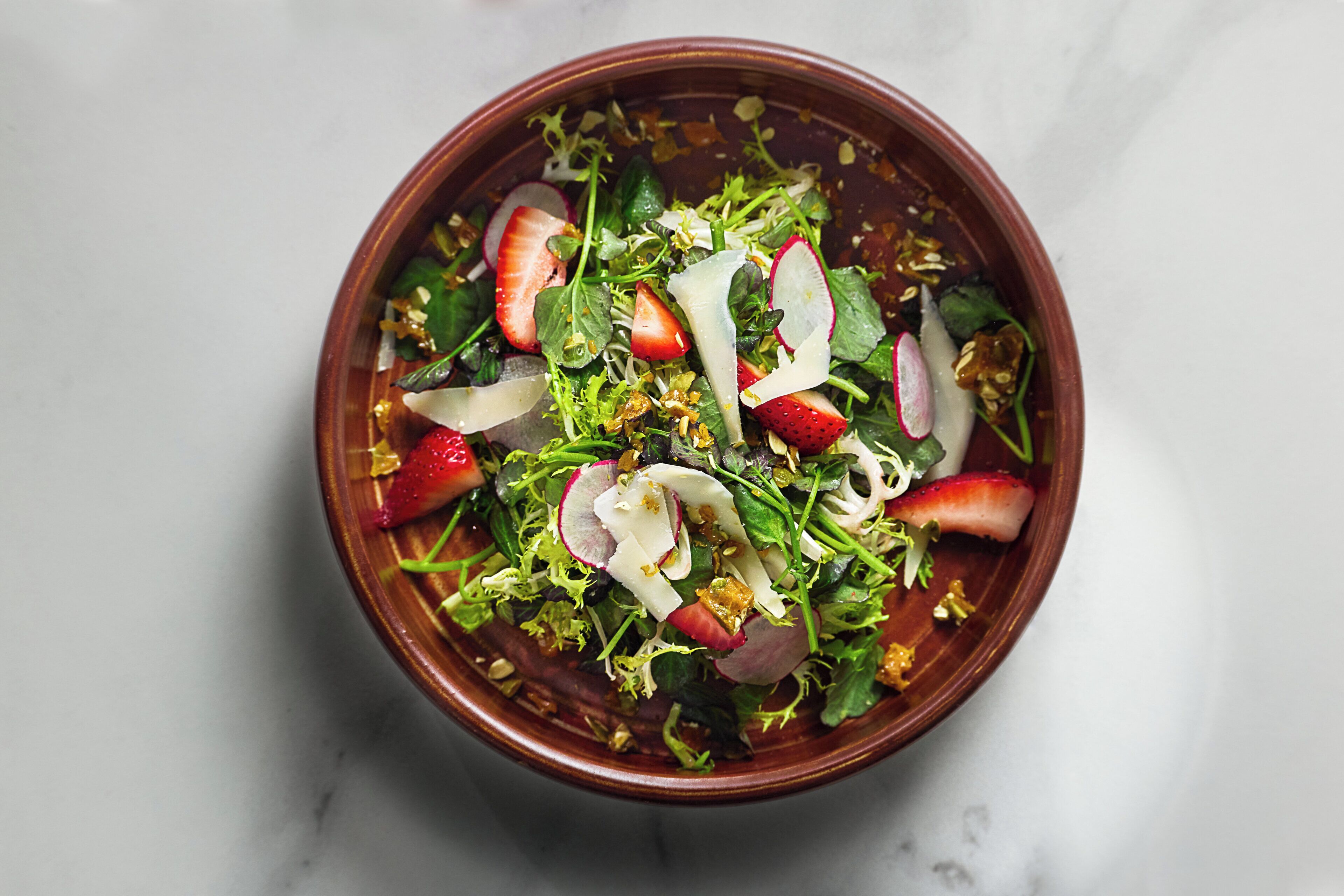 Un tazón de ensalada con diversas verduras y frutas.