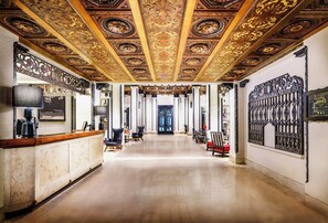 A grand hallway with ornate ceiling artwork, a reception desk, and a large decorative gate. - Hotel Spero, Vignette Collection by IHG (San Francisco)