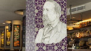 A bar area with a mural of a man, shelves of liquor bottles, and a patterned wall.