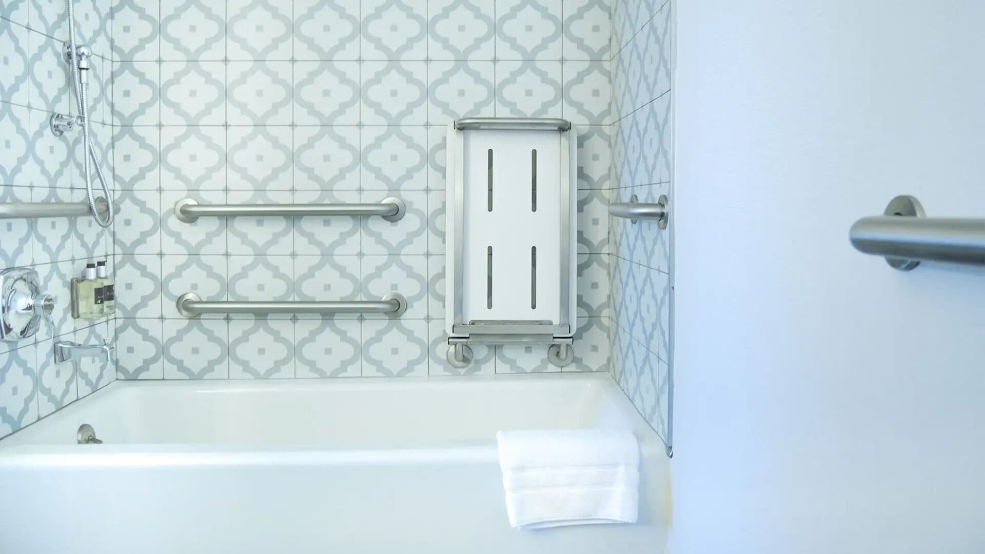 A bathroom with a bathtub, a towel rack, and a handrail.