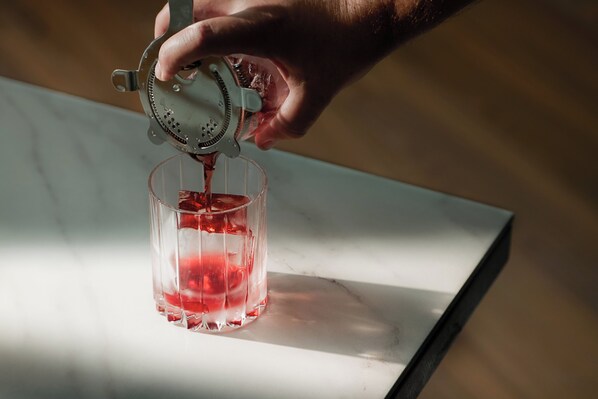 A hand pouring a red liquid into a clear glass. - Hotel Spero, Vignette Collection by IHG (San Francisco)