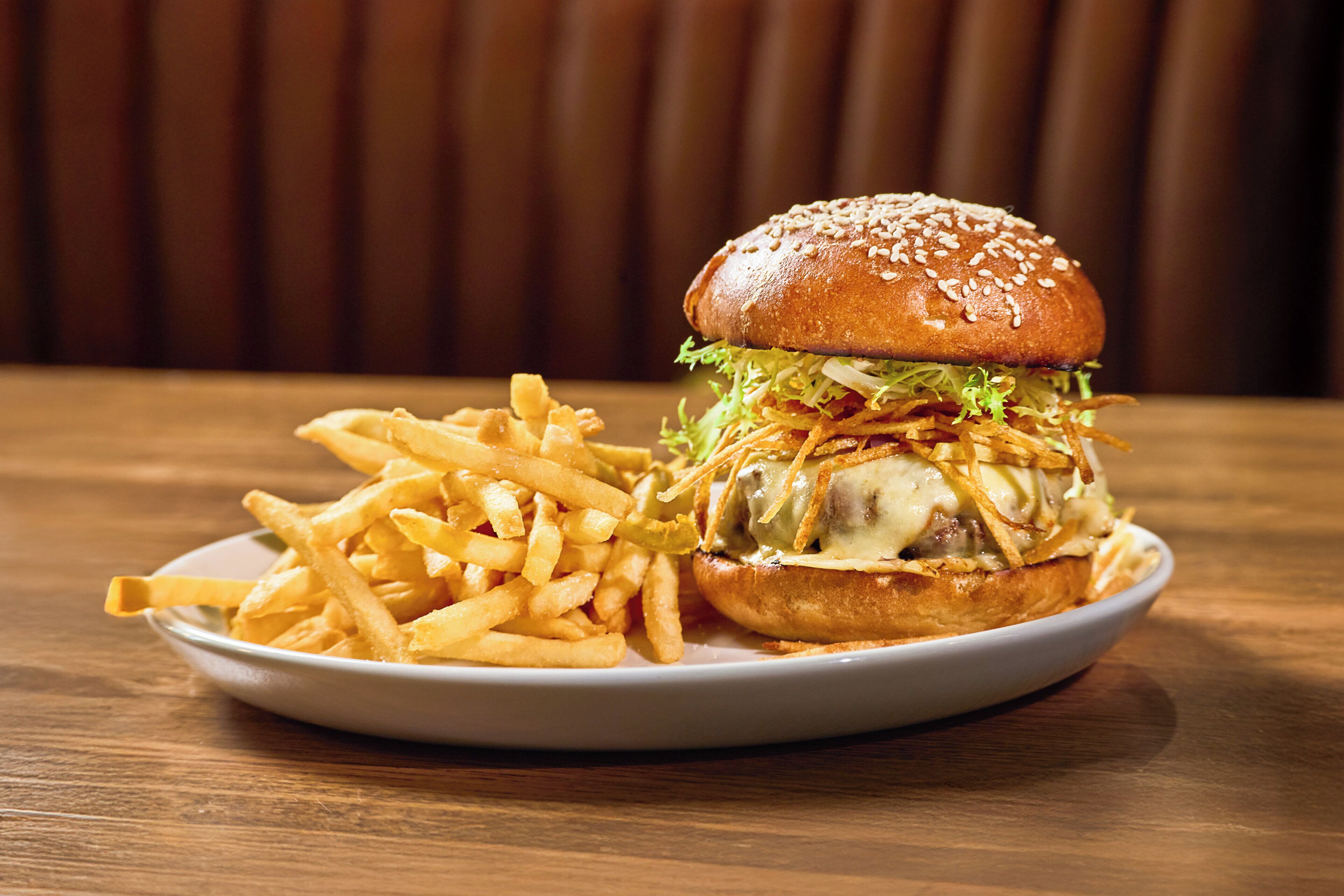 A plate with a burger and fries on a wooden table.