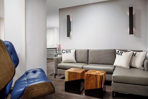 A modern living room with a grey sofa, blue leather chairs, and wooden side tables. - Hotel Spero, Vignette Collection by IHG (San Francisco)