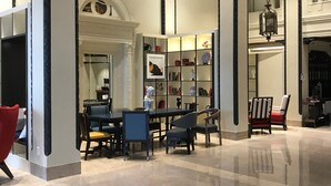 A spacious lobby with high ceilings, ornate ceiling details, and a central seating area with chairs and a table.