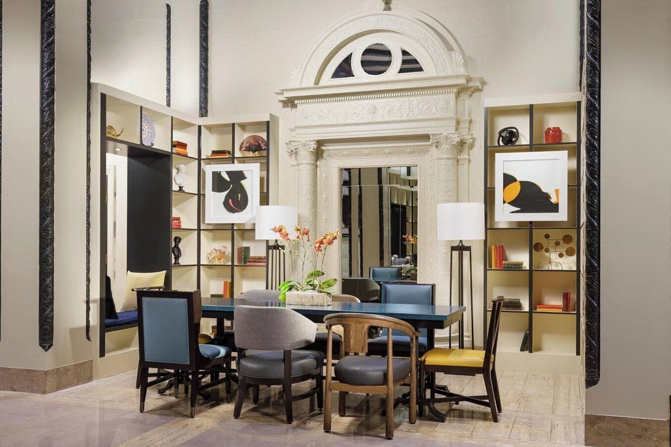 A dining area with a marble floor, a central table with chairs, and bookshelves on either side.