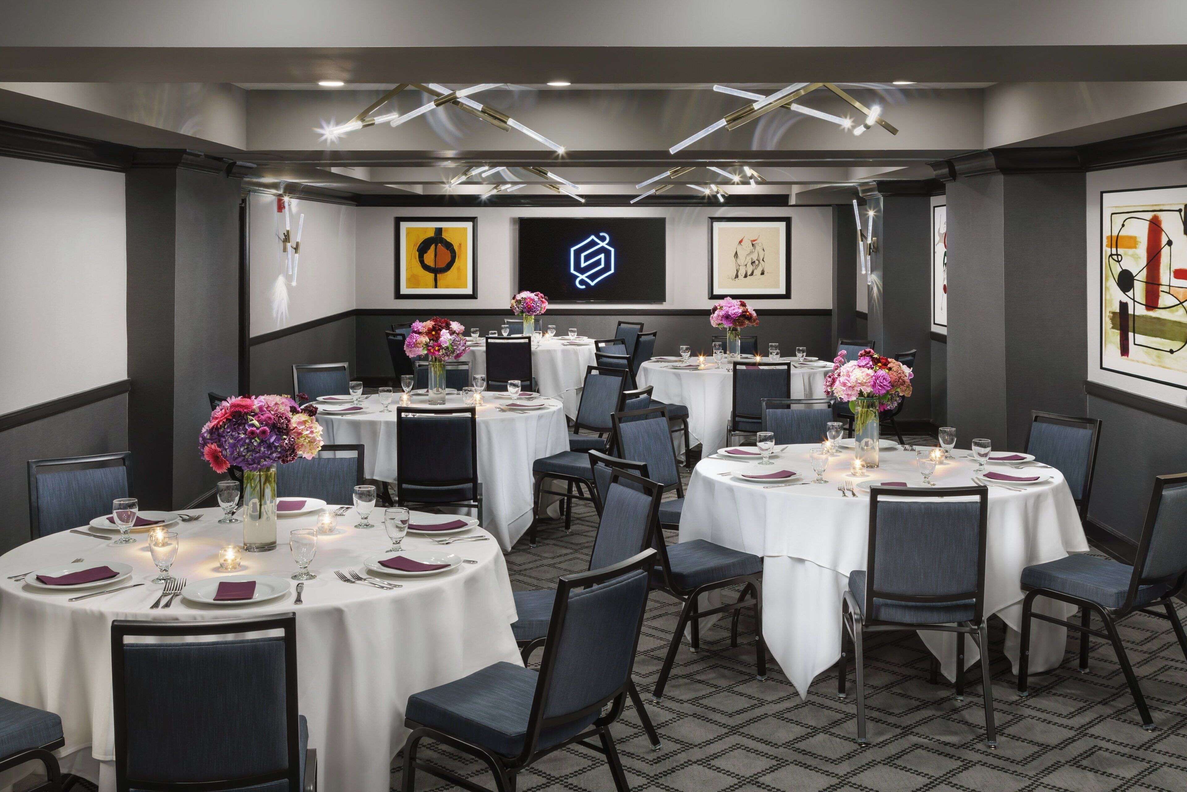 A conference room with round tables, chairs, and floral centerpieces.