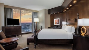 A hotel room with a large bed, a TV, a desk, and a view of the cityscape through large windows. - Renaissance Dallas North Hotel (Farmers Branch)